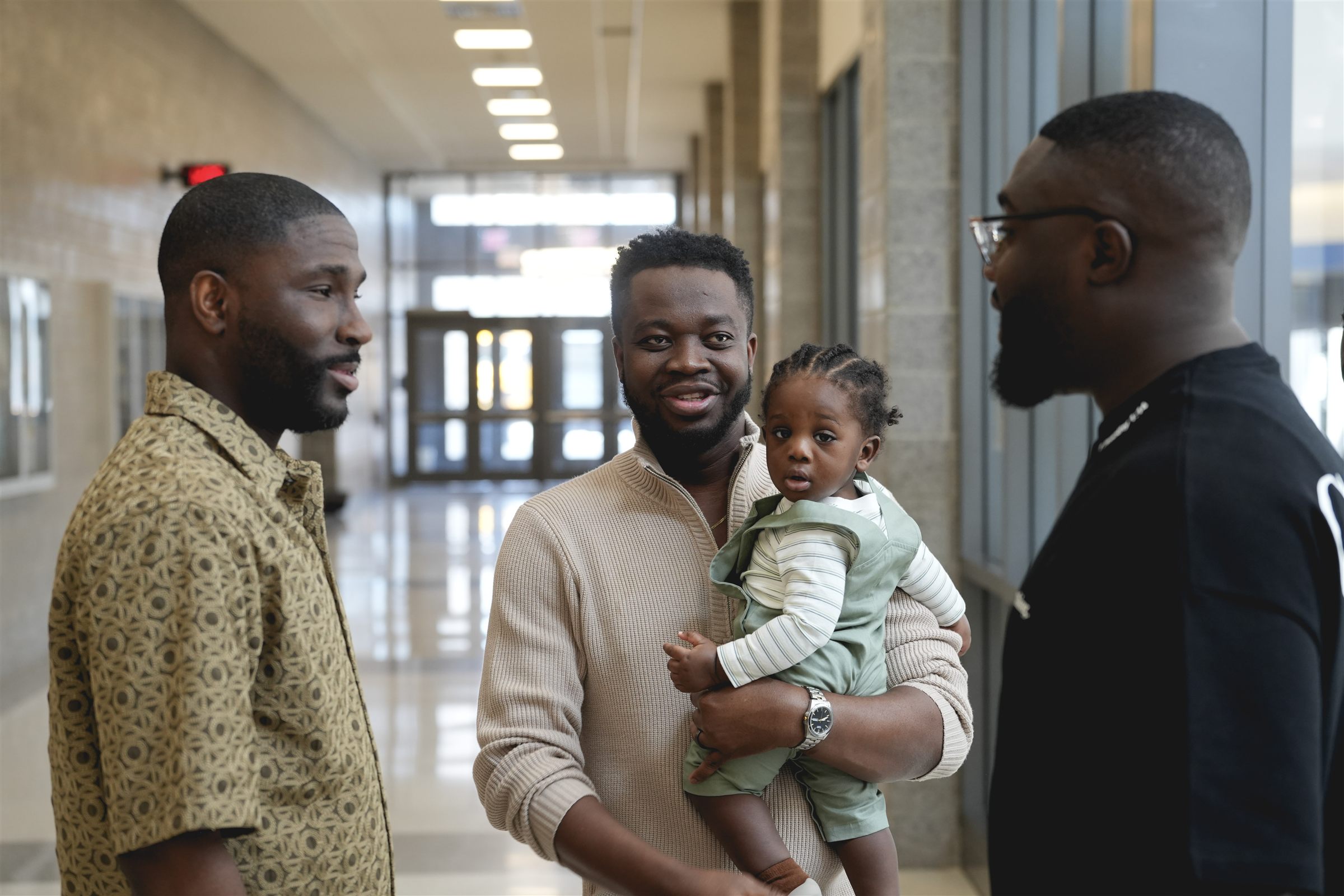 A father holding his baby, talking with friends